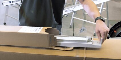 Person, die eine vorkonfektionierte Bodenschwelle aus einem Aufreißkarton entnimmt