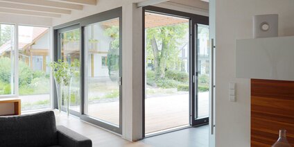 Großzügiger Wohnraum mit Hebeschiebetür und moderner Holzterrasse im Außenbereich