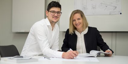 Zwei Mitarbeiter besprechen technische Zeichnung im Büro