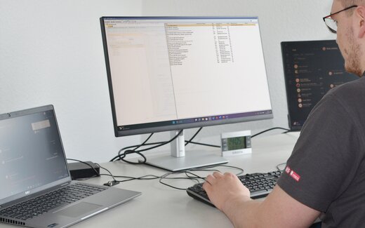 Person am Schreibtisch mit Tastatur und Monitor
