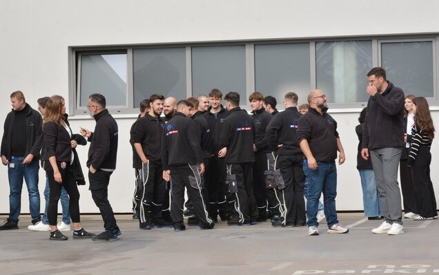 Mitarbeitergruppe in GU Arbeitskleidung vor Gebäude