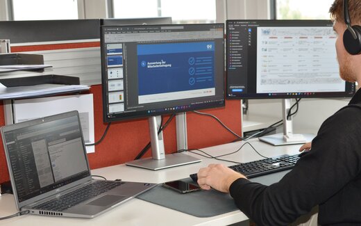 Person arbeitet an Büroarbeitsplatz mit Monitoren