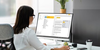 Frau arbeitet am PC mit dem Gretsch-Unitas Ausschreibungsportal für Bau- und Architektenprojekte
