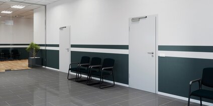 Moderner Büroflur mit Wartebereich und weißen Türen